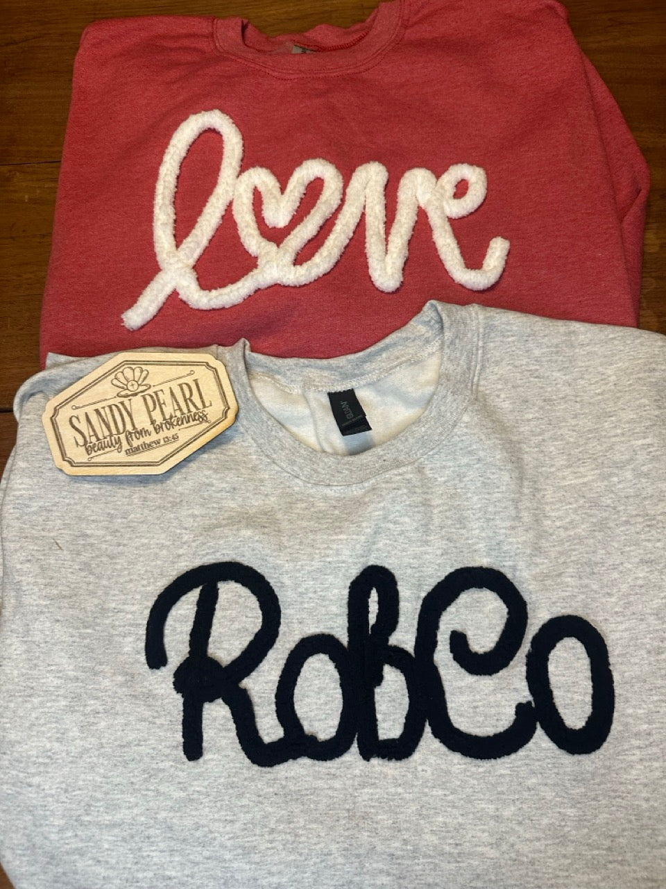 Yarn embroidered crewneck sweatshirts in multiple colors and designs including RobCo, Love, Devils, Nana, and East